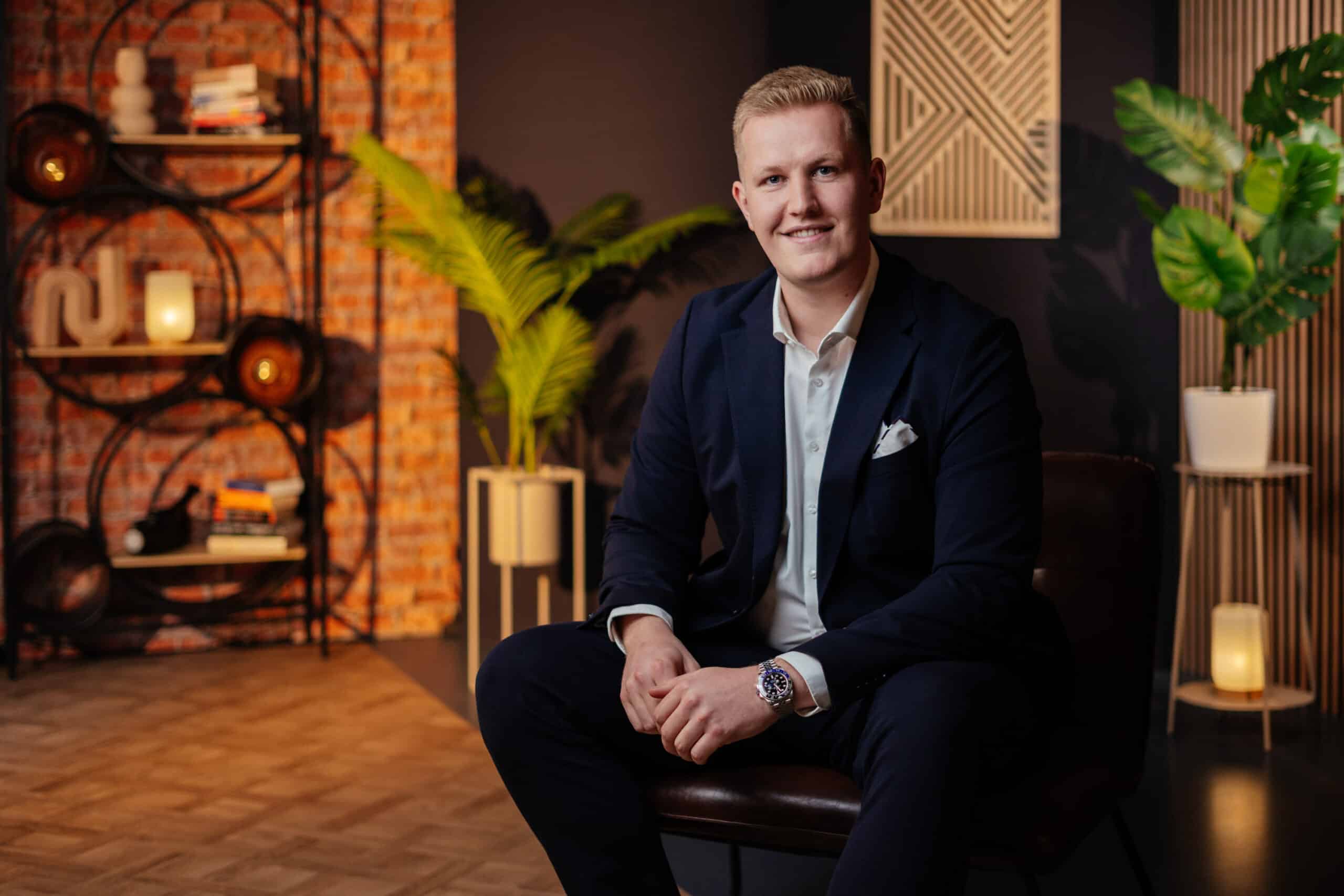 Lennard Schwarzer sitzend im modernen Büro mit Pflanzen und warmem Licht